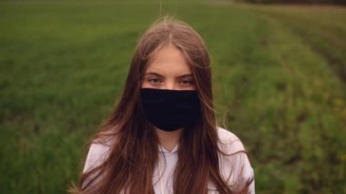 Koruyucu maskeli bir kadın rüzgar salgınında çırpınıyor. Covid-19 Coronavirus. 
