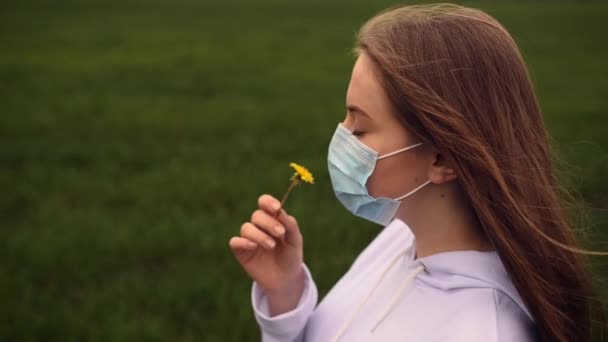 Woamn durch eine Maske schnüffelt eine gelbe Blume Löwenzahn Pandemie covid-19 — Stockvideo
