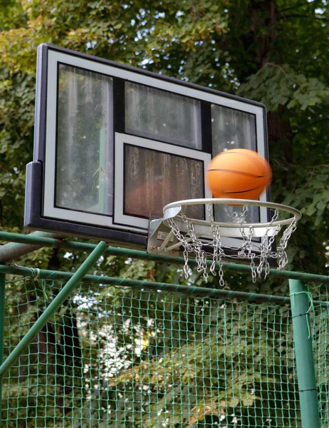 Basketball Board with Basket and Orange Ball Outdoors.