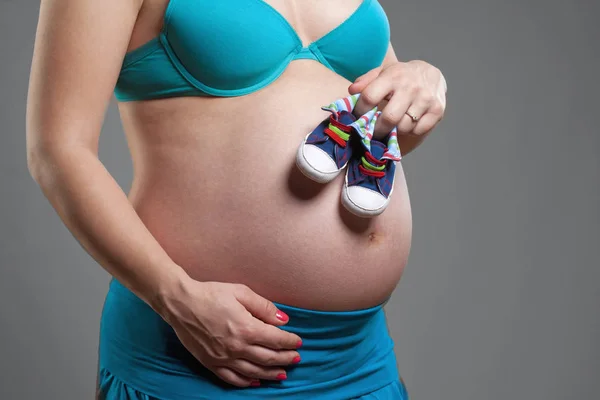Schwangere mit Händen, die Babyschuh halten. — Stockfoto