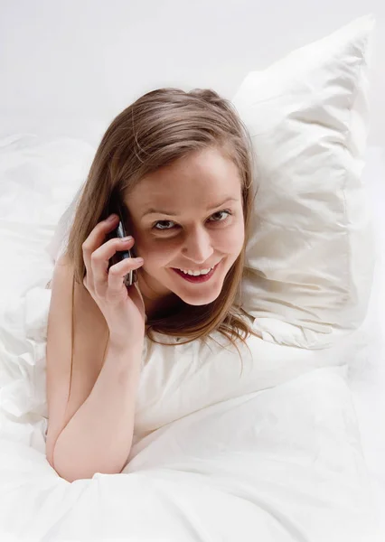 Vrouw in bed praten over telefoon. — Stockfoto