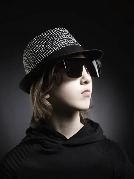 Portret van een jongen met blond haar in hoed en zwarte top. — Stockfoto