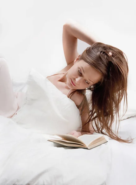 Vrouw in bed lezen van een boek. — Stockfoto