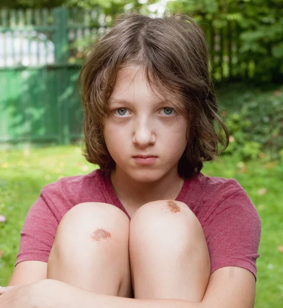 Junge mit geprellten Kniescheiben im Garten. — Stockfoto