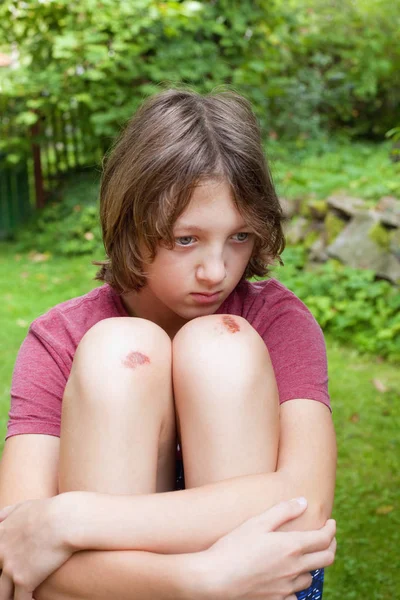 Junge mit geprellten Kniescheiben im Garten. — Stockfoto