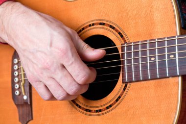 Akustik gitar çalan gitaristin parmakları. 