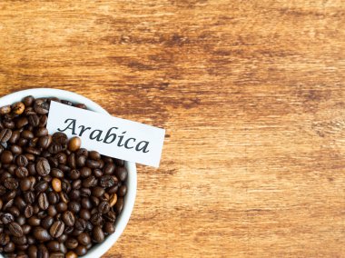 Eski ahşap arka plan üzerinde Arabica kahve çekirdekleri dolu kase, uzay kopyalayın, yat
