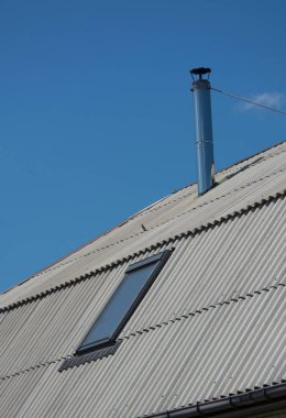 Metalik baca ve mavi gökyüzü altında ışıklık ile kayrak çatı