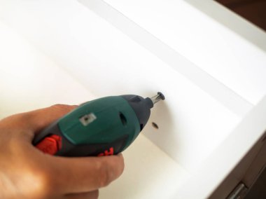 Elektrikli tornavida tutan ve ahşap mobilya kutusunda vida vidalama adam el. atış, DIY kapatın