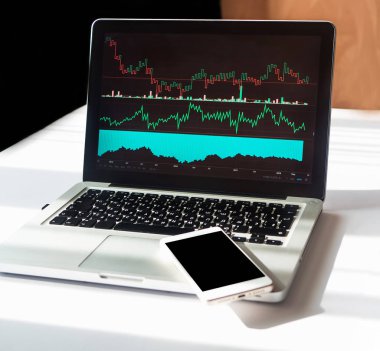 İş grafik ve grafik smartphone ve boşaltmak dizüstü bilgisayar ekranında. İşadamı çalışma yer