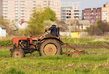 Kış buğday ekmek için toprak sonbaharda çiftçilik bir traktör sürücüsü. Arka plan ile çok katlı tarlayı traktör traktör sürücüsü yan görünüm evler