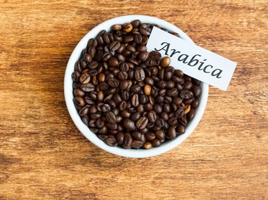 Arabica kahve çekirdekleri, düz ahşap arka plan üzerine bir kase koymak