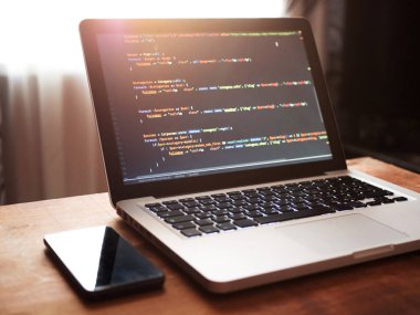 Bilgisayar kodu (web geliştirme) dizüstü bilgisayar ve cep telefonu masada