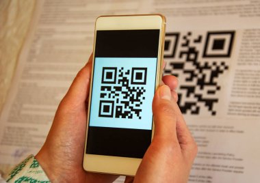 Cep telefonu tutarak ve tarama Qr kodu, nakitsiz ödeme iki kadın eli