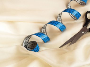 Bükülmüş şerit metre ve makas krem tül, makro çekim, dikiş kavramı mavi