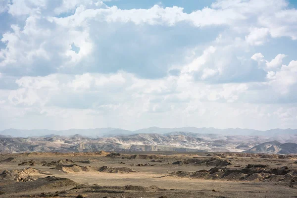 Dry egyptian desert with mountains under clouds. Lifeless desert, martian landscape