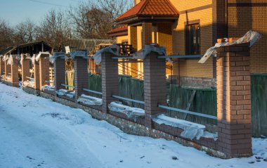 Yeni evde sütunlarla bitmemiş tuğla çit