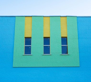 Üç dar dikey pencere yeşil ve sarı renk mavi tuğla duvar