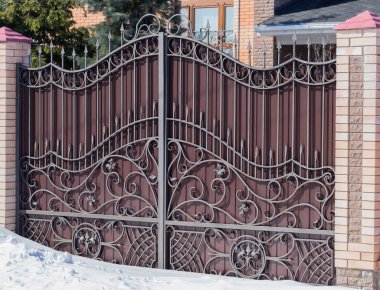 Güneş ışığı altında sahte desen ve tuğla sütunlarla kahverengi Iron gate