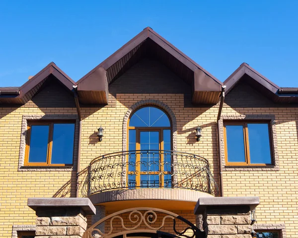 Facade of modern brick house with forgery balcony, windows and rain gutters