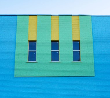 Üç dar dikey pencere yeşil ve sarı renk mavi tuğla duvar