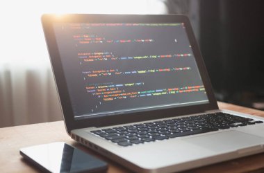Bilgisayar kodu (web geliştirme) dizüstü ve güneş ışığı altında mobil akıllı telefon