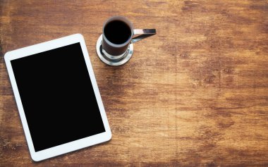 Tablet ve ahşap masa üzerinde kahve. Siyah boş yer üstünde belgili tanımlık perde. Yukarıdan görüntüleyin. Düz yatıyordu kopya alanı