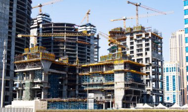 Dört modern çok öykülü bina yapım aşamasında. Büyük inşaat alanında vinçler ve iskele