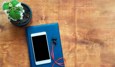 Ahşap masa smartphone, mavi defter ve kırmızı kulaklık ile. Üstten görünüm kopya alanı, düz ile yatıyordu.