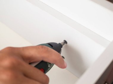 Elektrikli tornavida tutan ve ahşap mobilya kutusunda vida vidalama adam el. atış, DIY kapatın