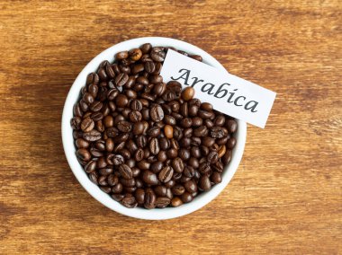 Arabica kahve çekirdekleri eski bir ahşap masa üzerinde kase
