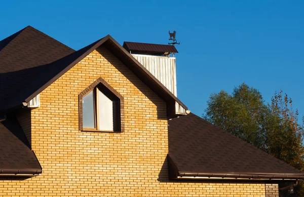 Techo de varios niveles de nueva casa de ladrillo con ventana y chimenea — Foto de Stock