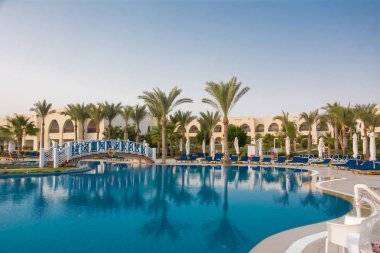 Turkuaz su, ahşap köprü ve güneşlik ile yüzme havuzu