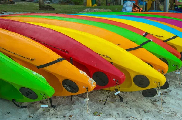 Varios kayaks coloridos tumbados boca abajo en la playa de arena, de cerca — Foto de Stock