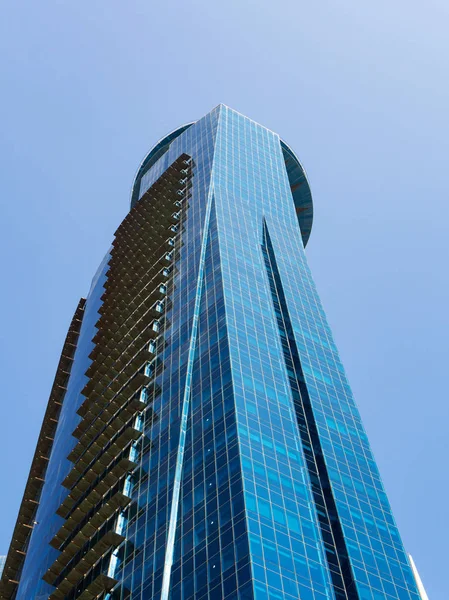 Gratte-ciel moderne avec façade vitrée sur fond bleu ciel. Ailettes — Photo