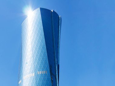 Al Bidda Kulesi güneş vurgulamak ve copyspace ile mavi arka plan üzerinde. Camlı cepheli modern gökdelen