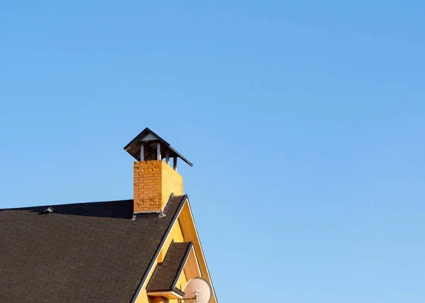 Primer plano de chimenea de ladrillo pelado en el techo bajo el cielo azul — Foto de Stock