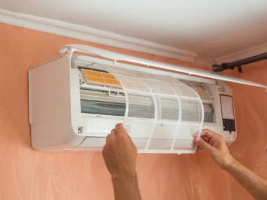 Changing filter in air conditioner on the wall clipart