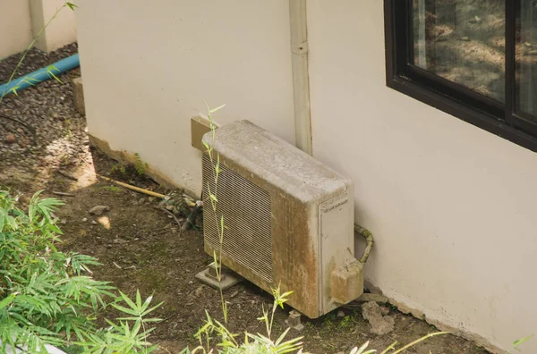 Old metal exterior fitted air conditioning unit staying on the ground needing maintenance