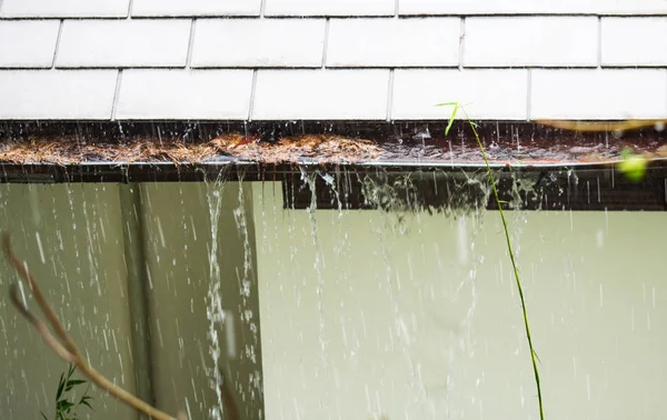 Närbild på igensatt regn rännstenen i regnet. Hem rännor, rännor — Stockfoto