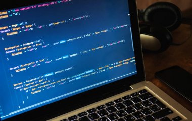 Wor üzerinde cep telefonu ve kulaklık ile dizüstü bilgisayarın ekranında Php kodu