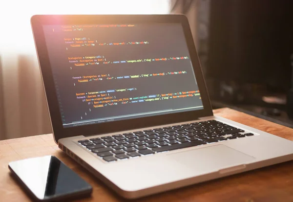 Código de computador no laptop (desenvolvimento web) e celular — Fotografia de Stock