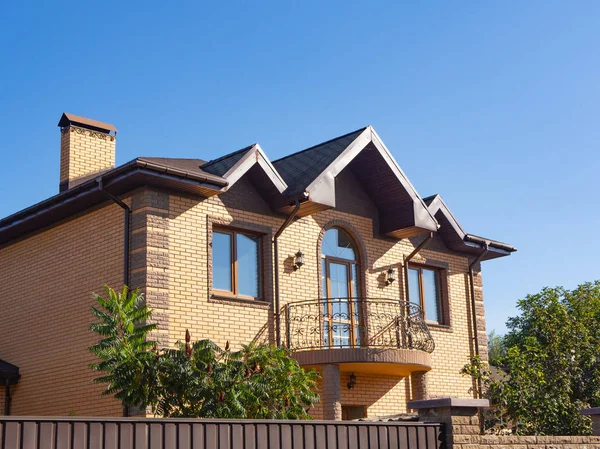 Modern cottage with forgery balcony and brick facade. Blue sky b