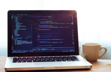 Laptop php kodu (Web geliştirme) ve beyaz fincan. Programcı çalışma alanı