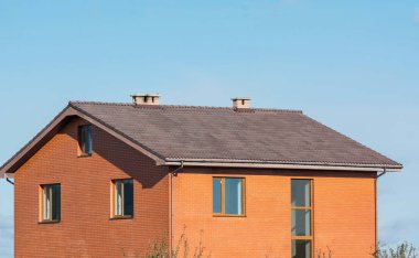 Mavi gökyüzü altında pencereler ve Bacalar ile büyük tuğla bina