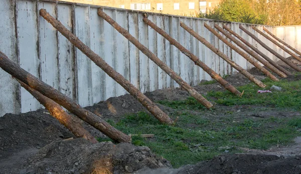 Бетонный забор, поддерживаемый стволами деревьев — стоковое фото