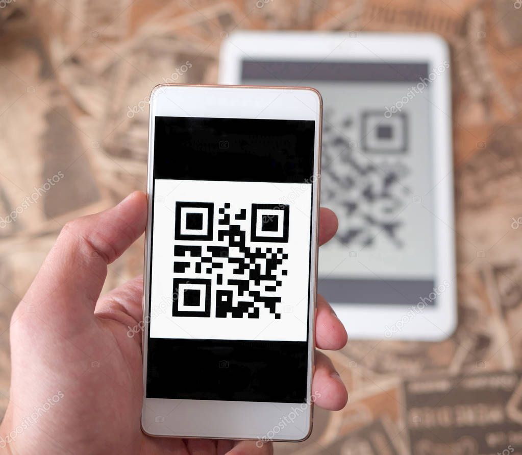 Man hand scanning qr code from the tablet using mobile phone.