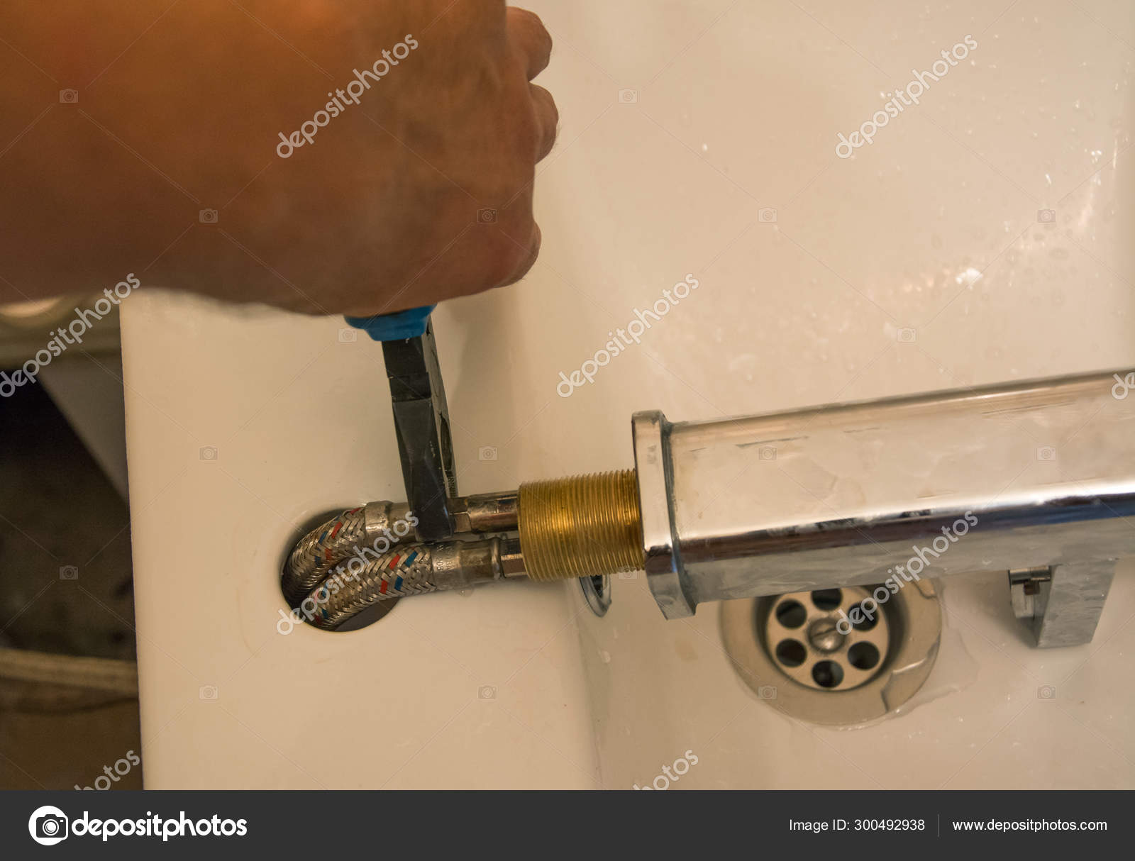 Plumber Repairs A Leaky Faucet In Bathroom Stock Photo