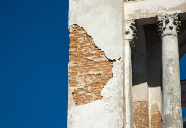 Alçı duvardan düşen ve tuğla gösteren, mavi gökyüzü bac