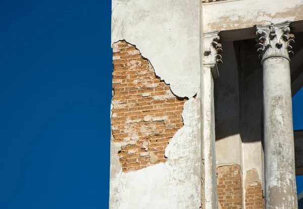 Alçı duvardan düşen ve tuğla gösteren, mavi gökyüzü bac